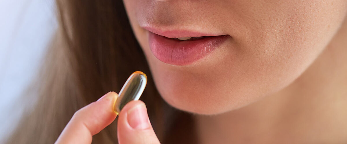 Woman taking hemp oil softgel capsule